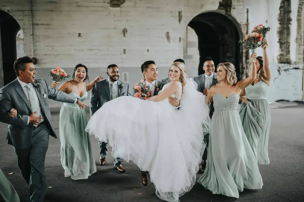 Wedding party with bridesmaids in sage green dresses and groomsmen in gray suits